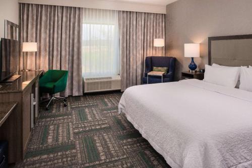 une chambre d'hôtel avec un lit, une chaise et une télévision dans l'établissement Hampton Inn - Paragould, à Paragould