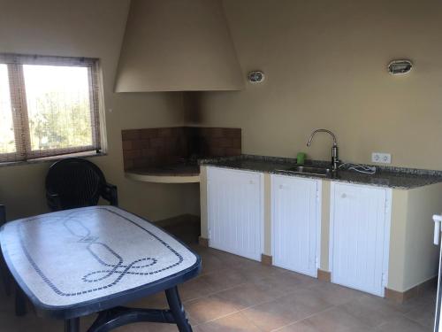 a kitchen with a sink and a table with a chair at Casa tranquila in Teulada