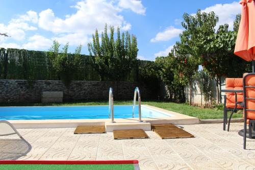 a swimming pool with orange chairs and an umbrella at Casa de Vale Benfeito - Turismo Rural in Macedo de Cavaleiros
