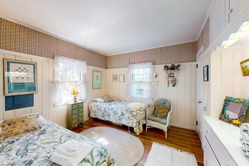 a bedroom with two beds and a chair at The Spray in Harwich Port