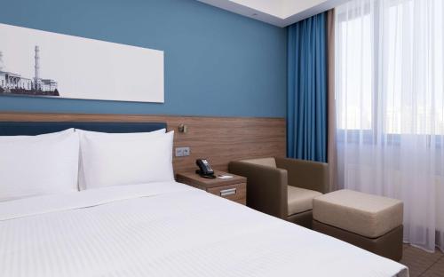 a hotel room with a bed and a chair at Hampton By Hilton Astana Triumphal Arch in Astana
