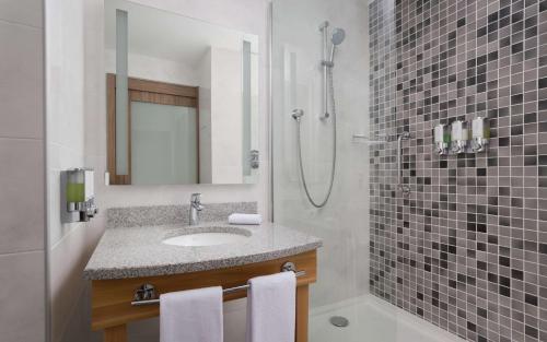 a bathroom with a sink and a shower at Hampton By Hilton Astana Triumphal Arch in Astana