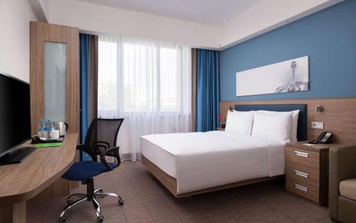 a hotel room with a bed and a desk with a computer at Hampton By Hilton Astana Triumphal Arch in Astana