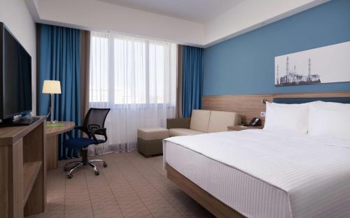a hotel room with a bed and a desk and a television at Hampton By Hilton Astana Triumphal Arch in Astana