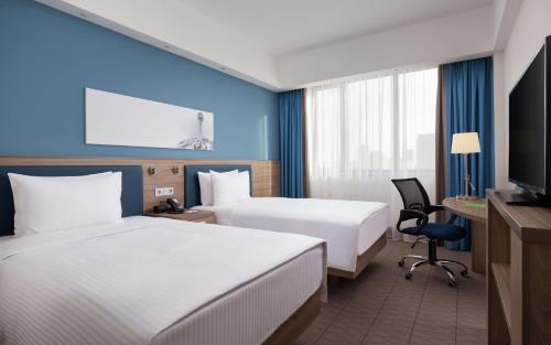 a hotel room with two beds and a tv at Hampton By Hilton Astana Triumphal Arch in Astana