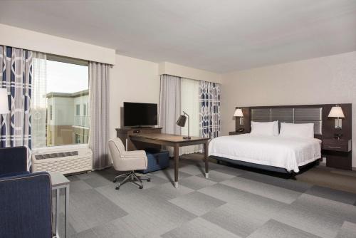 Habitación de hotel con cama, escritorio y TV. en Hampton Inn & Suites Indianapolis-Keystone, IN, en Indianápolis