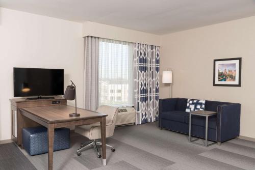a hotel room with a desk and a couch and a television at Hampton Inn & Suites Indianapolis-Keystone, IN in Indianapolis