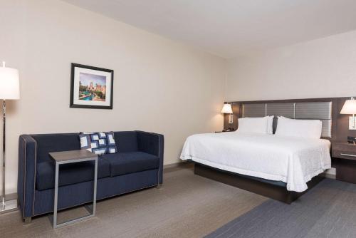 a hotel room with a bed and a blue couch at Hampton Inn & Suites Indianapolis-Keystone, IN in Indianapolis