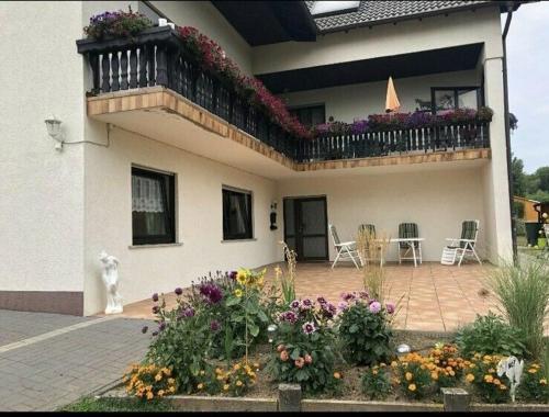 a house with a balcony and a patio with flowers at Am Mühlenberg in Ohlweiler