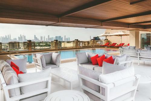 a rooftop patio with white chairs and a pool at DoubleTree by Hilton Dubai Al Jadaf in Dubai