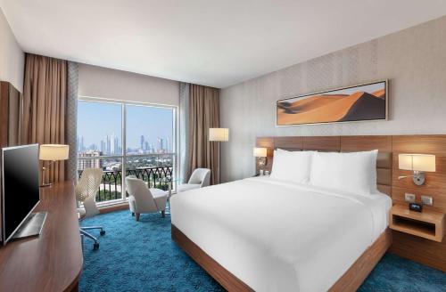 a hotel room with a bed and a desk and a window at DoubleTree by Hilton Dubai Al Jadaf in Dubai