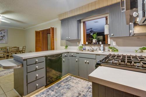 a kitchen with gray cabinets and a sink and a stove at Spacious Little Rock Home with Patio - 9 Mi to Dtwn! in Little Rock