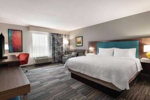a hotel room with a large bed and a chair at Hampton Inn Champaign Southwest in Champaign