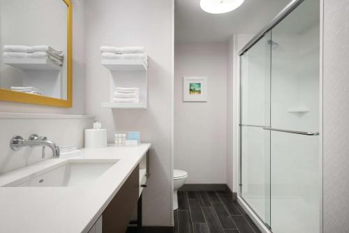 a white bathroom with a sink and a shower at Hampton Inn Champaign Southwest in Champaign