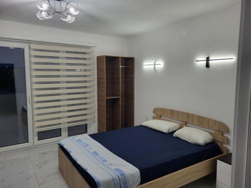 a bedroom with a blue bed and a window at Jordanovi Premium Apartment in Kavadarci