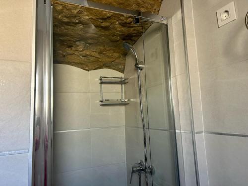 una doccia con porta in vetro in bagno di Casa Cueva Sol y Luna Setenil a Setenil