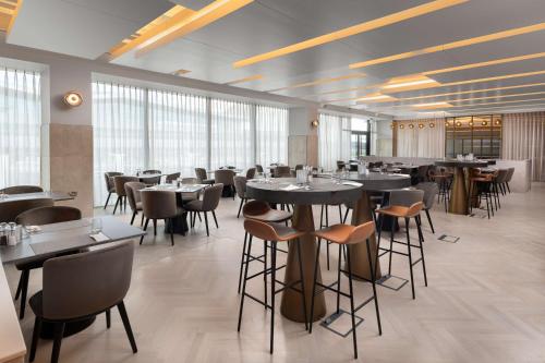 a dining room with tables and chairs and windows at Hilton Garden Inn Silverstone in Towcester