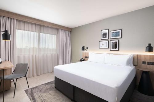 a hotel room with a large bed and a desk at Hilton Garden Inn Silverstone in Towcester
