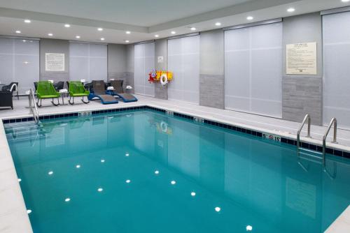 une grande piscine avec des chaises vertes dans un bâtiment dans l'établissement Hampton Inn & Suites Adrian, Mi, à Adrian