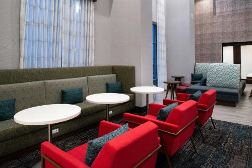 a waiting room with tables and red chairs at Hampton Inn & Suites Adrian, Mi in Adrian