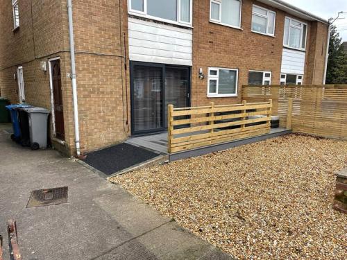 a wooden bench in front of a brick building at Modern 2BR Flat in Sale - Peaceful Stay in M33 - Great Transport Links in Broadheath