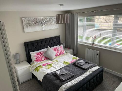 a bedroom with a bed with pink flowers on it at Comfortable ground floor, 2 BR modern Apartment in Broadheath