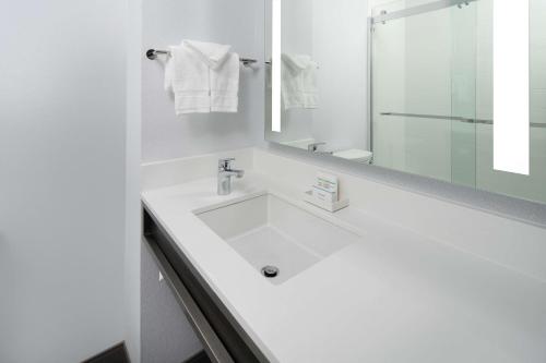 Baño blanco con lavabo y espejo en Hilton Garden Inn Irvine Spectrum Lake Forest, en Lake Forest
