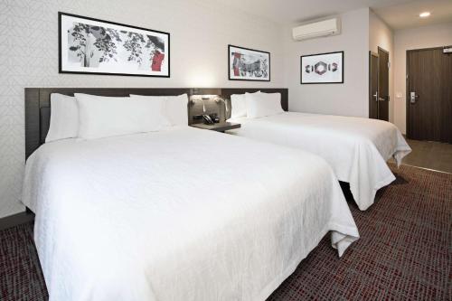 two beds in a hotel room with white sheets at Hilton Garden Inn Irvine Spectrum Lake Forest in Lake Forest