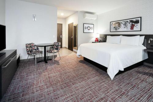 a hotel room with a large bed and a table at Hilton Garden Inn Irvine Spectrum Lake Forest in Lake Forest