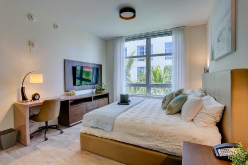 a bedroom with a bed and a desk and a television at New! Beach Access with Rooftop Pool in Hollywood