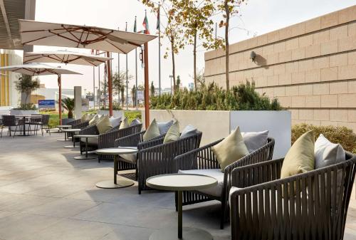 eine Reihe von Stühlen, Tischen und Sonnenschirmen auf einer Terrasse in der Unterkunft Hilton Garden Inn Kuwait in Kuwait