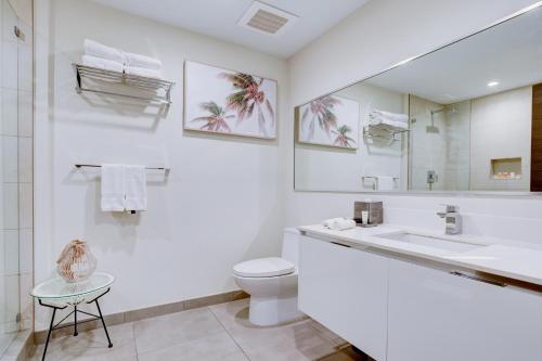 a bathroom with a sink and a toilet and a mirror at New! Beach Access with Rooftop Pool in Hollywood