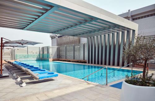 a swimming pool with blue lounge chairs in a building at Hilton Garden Inn Kuwait in Kuwait