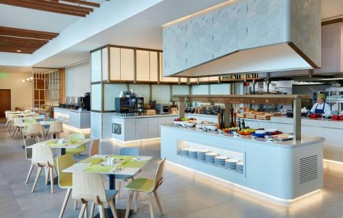 a restaurant with tables and chairs and a kitchen at Hilton Garden Inn Kuwait in Kuwait