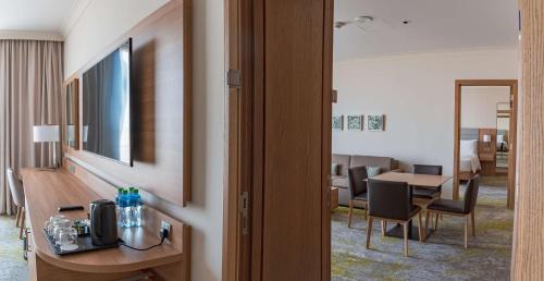 a hotel room with a desk and a table with chairs at Hilton Garden Inn Kuwait in Kuwait