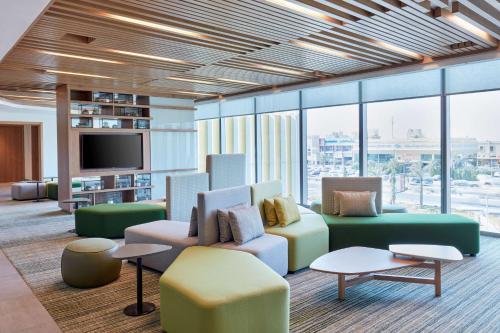 a lobby with a couch and chairs and a tv at Hilton Garden Inn Kuwait in Kuwait