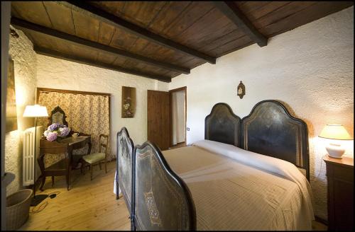 a bedroom with a large bed and a desk at Agriturismo Famiglia al Castello Di Bagnolo in Bagnolo Piemonte