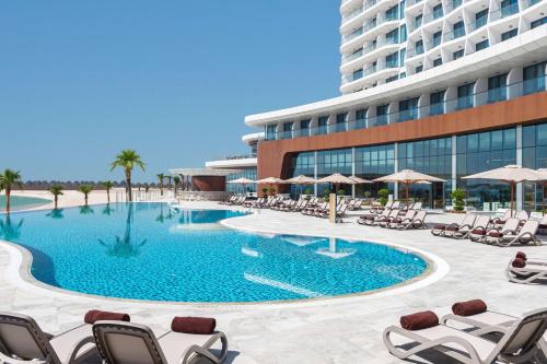una piscina di fronte a un hotel con sedie e un edificio di Hampton by Hilton Marjan Island a Ras al Khaimah