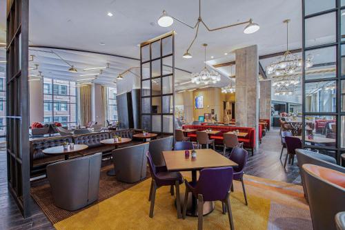 um restaurante com mesas, cadeiras e janelas em Canopy By Hilton Jersey City Arts District em Jersey City