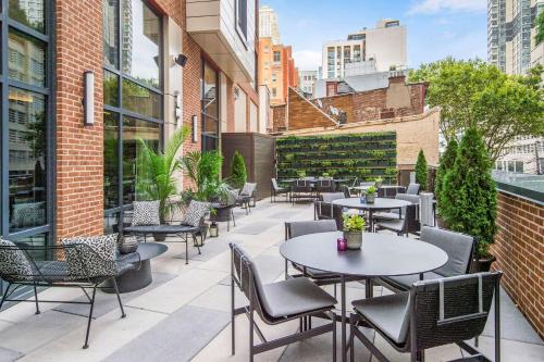 an outdoor patio with tables and chairs and buildings at Canopy By Hilton Jersey City Arts District in Jersey City