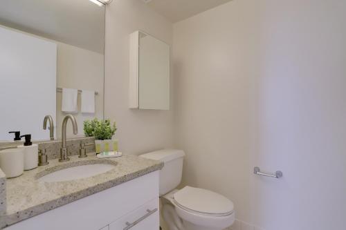 a white bathroom with a toilet and a sink at Gorgeous Apt with Rooftop City View @Pentagon City in Arlington