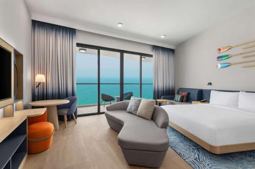 a hotel room with a large bed and a couch at Hampton by Hilton Marjan Island in Ras al Khaimah