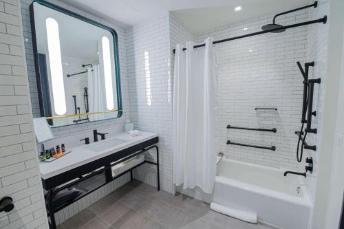 a white bathroom with a sink and a tub and a mirror at Canopy By Hilton Jersey City Arts District in Jersey City