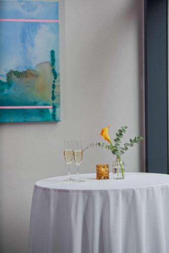a white table with two wine glasses and a vase at Canopy By Hilton Jersey City Arts District in Jersey City