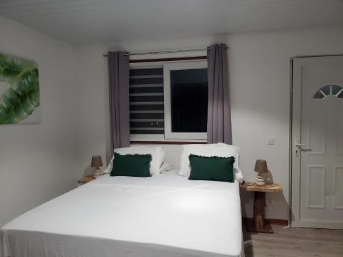 Hauru的住宿－Fare Mihiau 2，卧室内的一张带两个绿色枕头的白色床