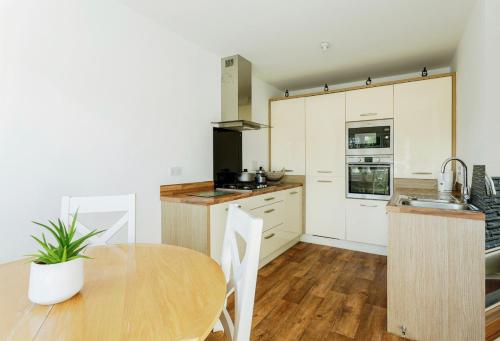 uma cozinha com armários brancos e uma mesa de madeira em Abbot House em Manchester
