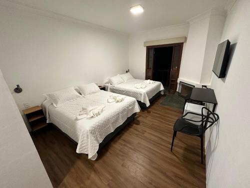 a hotel room with two beds and a television at Flat Acolhedor para 5 Pessoas em Campos do Jordão in Campos do Jordão