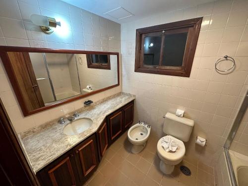 a bathroom with a sink and a toilet and a mirror at Flat Acolhedor para 5 Pessoas em Campos do Jordão in Campos do Jordão