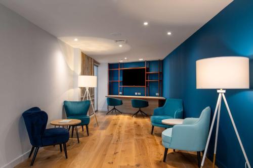 a waiting room with blue chairs and a table at Hampton by Hilton Canterbury in Canterbury