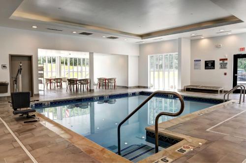 una piscina con mesas y sillas en un edificio en Hilton Garden Inn Bel Air, Md, en Bel Air